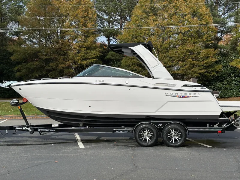 Slide: The Image of 2025 Monterey 258SS boat on trailer, parked outdoors with trees in background. - 25