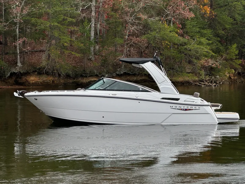 Slide: The Image of 2025 Monterey 258SS boat on a calm lake with forested background. - 6