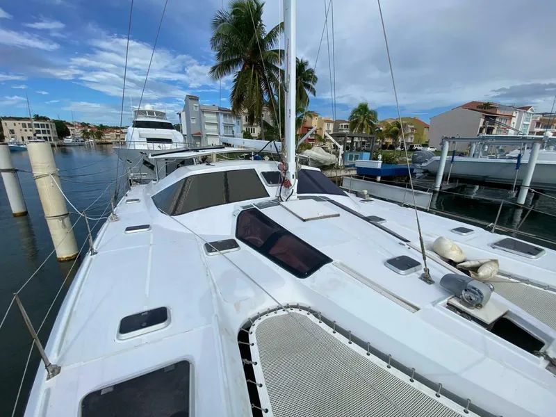 The Image of Sailing catamaran "Privilege Boolean" docked in marina, 1993 model, with palm trees and buildings nearby. - 1