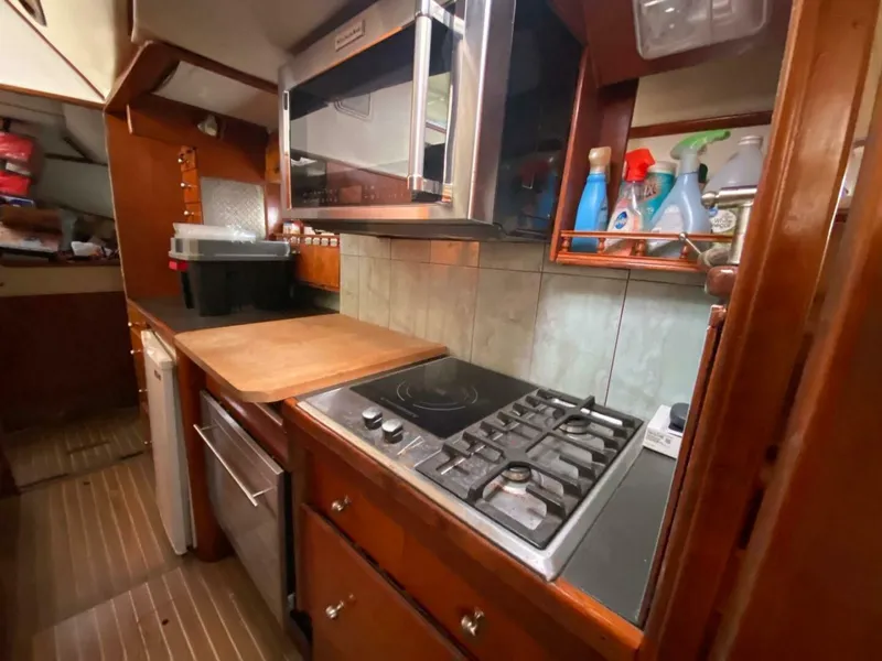 Slide: The Image of Kitchen area in a 1993 Privilege Boolean yacht with stove, microwave, and wooden cabinetry. - 13
