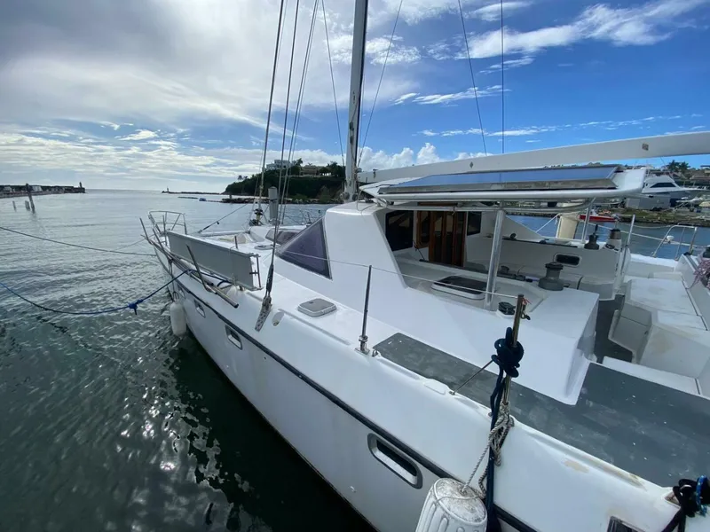 Slide: The Image of Sailing catamaran Privilege Boolean 1993 docked in a serene marina under a partly cloudy sky. - 3