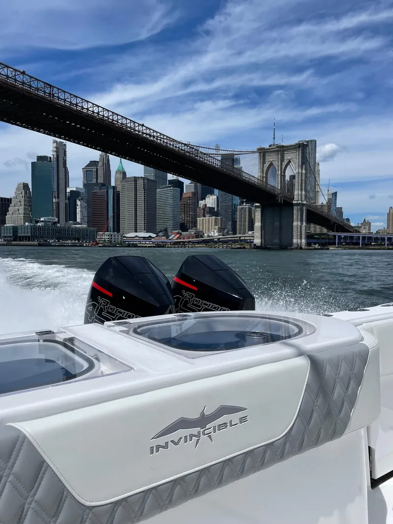 Slide: The Image of Invincible 40 Catamaran cruising near Brooklyn Bridge, 2022 model, city skyline in background. - 2