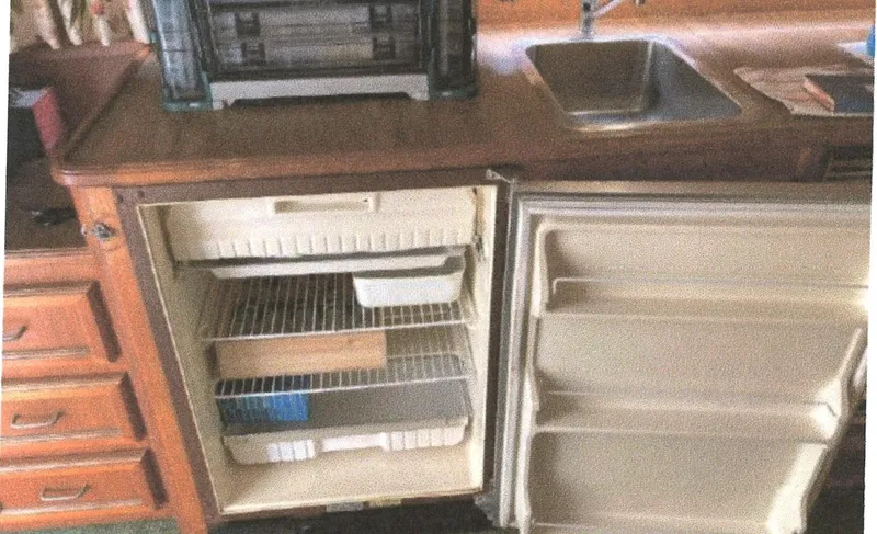Slide: The Image of 1983 Egg Harbor 33 Convertible kitchen with open fridge, wooden cabinets, and sink. - 10