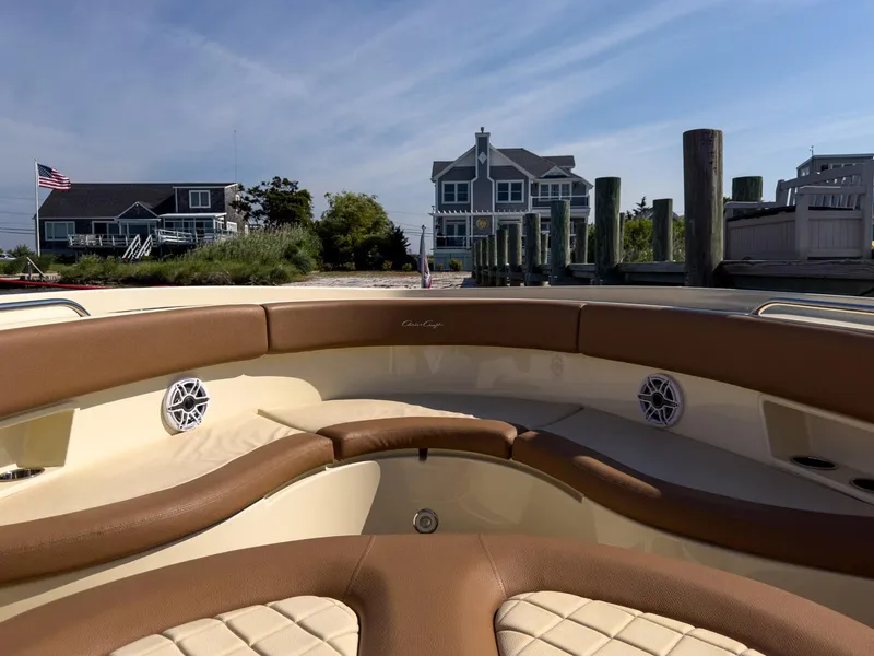 Slide: The Image of 2019 Chris-Craft 30 Catalina boat interior with brown leather seating, docked near waterfront homes. - 14