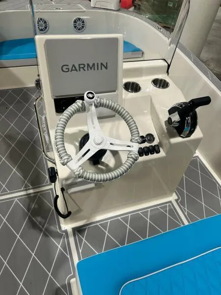 Slide: The Image of 2024 BlueCat 17 LF boat console with Garmin system, steering wheel, and blue seating. - 6