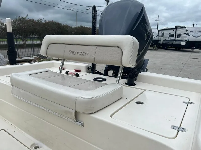 Slide: The Image of ShearWater 23LTZ 2012 boat with cushioned seating and outboard motor in a parking area. - 7