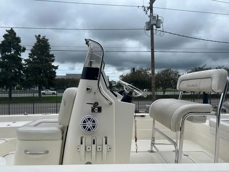 Slide: The Image of 2012 ShearWater 23LTZ boat interior with steering console and seating, under cloudy sky. - 9