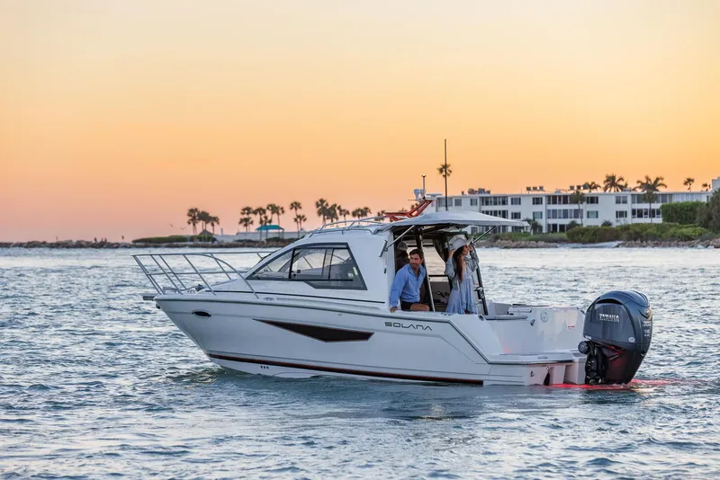 Slide: The Image of Solara S-250 Coupe 2025 cruising at sunset near coastal buildings. - 2