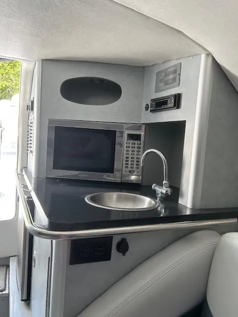 Slide: The Image of 2006 Baja 35 Outlaw boat interior with kitchenette, featuring a microwave and sink. - 12