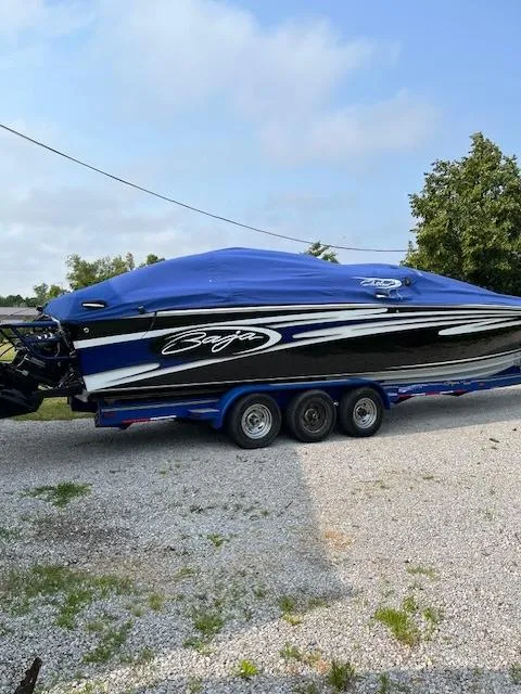 Slide: The Image of 2006 Baja 35 Outlaw boat with blue cover on trailer, parked outdoors. - 18