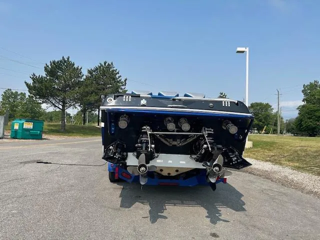 Slide: The Image of 2006 Baja 35 Outlaw boat rear view, parked on pavement, showcasing dual propellers. - 26