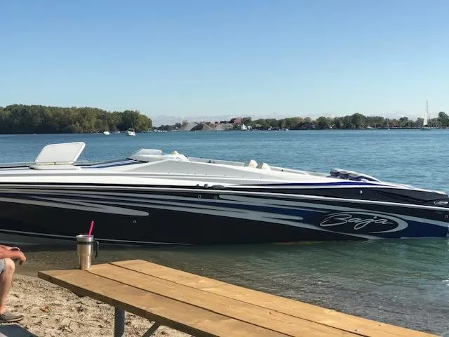 Slide: The Image of 2006 Baja 35 Outlaw speedboat docked on a sunny lakeside beach. - 5