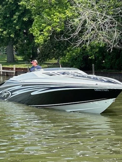 Slide: The Image of 2006 Baja 35 Outlaw speedboat on a calm lake with lush greenery. - 7