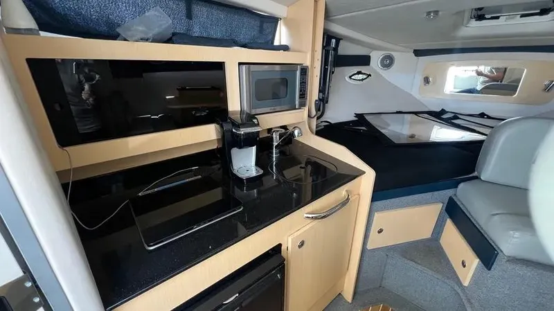 Slide: The Image of 2011 Bayliner 285 Cruiser interior with kitchenette, microwave, and seating area. - 18