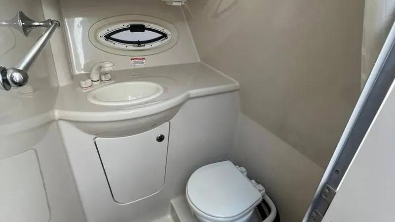 Slide: The Image of 2011 Bayliner 285 Cruiser bathroom with sink, toilet, and porthole window. - 22