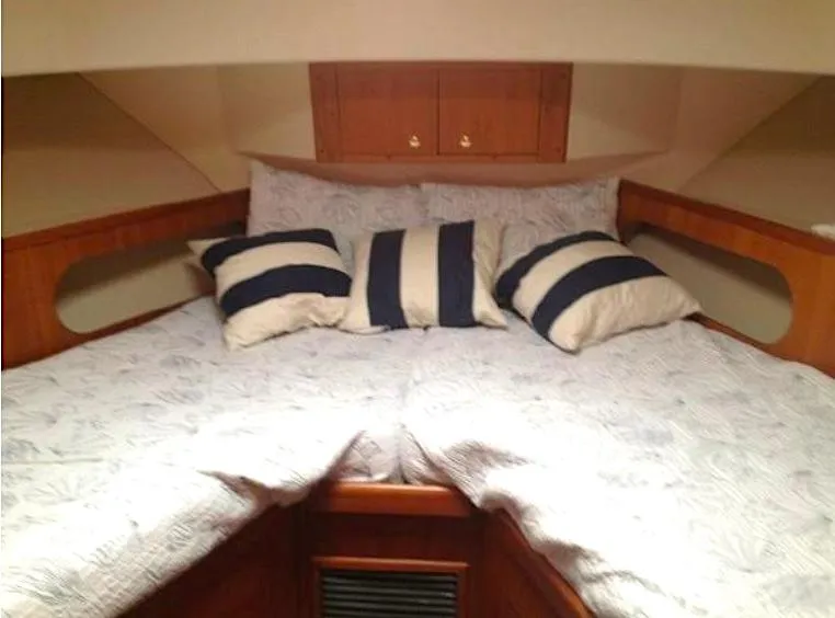 Slide: The Image of Cozy cabin interior of 2000 Mainship 430 Trawler with striped pillows and wooden accents. - 14