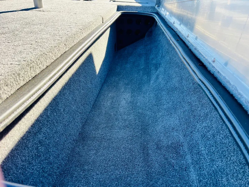 Slide: The Image of 2025 Tracker Pro Team 190 boat storage compartment, carpeted interior. - 15