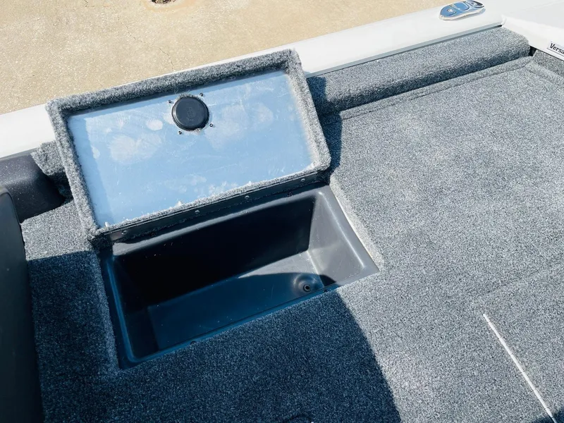 Slide: The Image of 2025 Tracker Pro Team 190 boat storage compartment with open lid, featuring carpeted interior. - 27