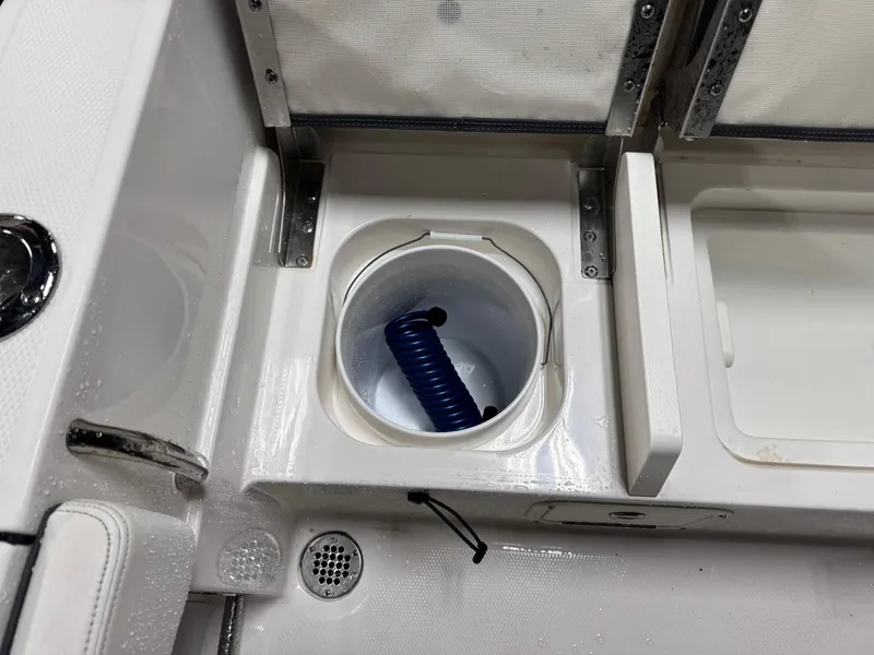 Slide: The Image of 2022 Robalo R230 Center Console boat storage compartment with coiled blue hose. - 18