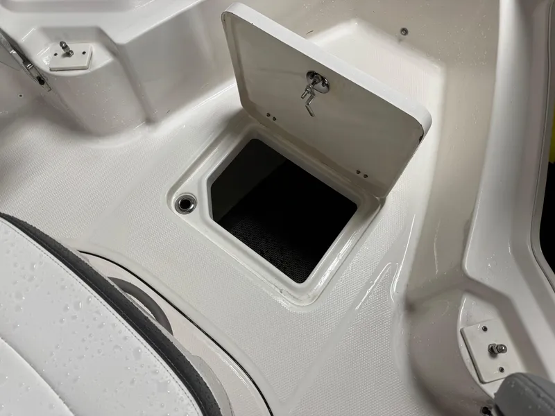 Slide: The Image of 2022 Robalo R230 Center Console storage compartment with open hatch and key. - 24