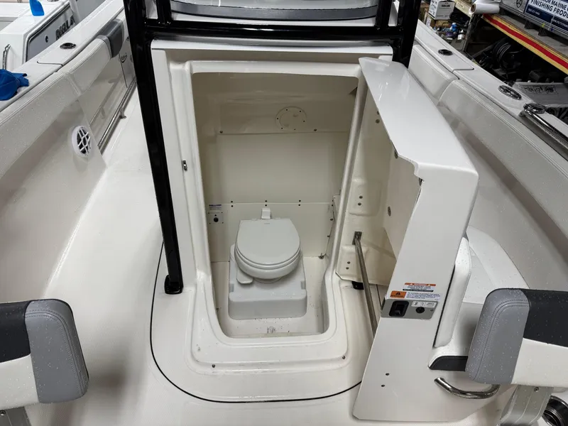 Slide: The Image of 2022 Robalo R230 Center Console boat interior with open marine toilet compartment. - 26