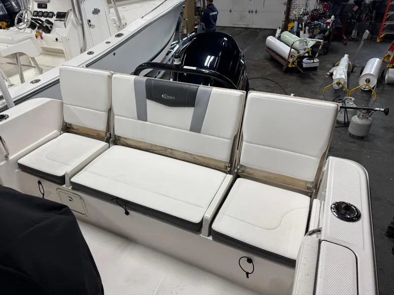 Slide: The Image of 2022 Robalo R230 Center Console boat with white cushioned seating in a workshop. - 8