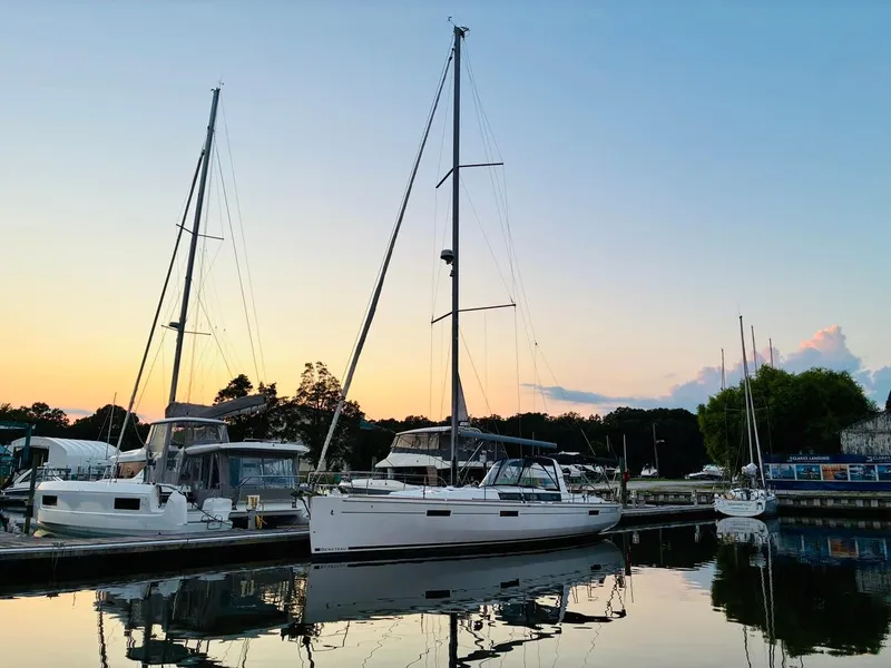 Slide: The Image of 2017 Beneteau Oceanis 45 sailboat docked at sunset, reflecting on calm water. - 2
