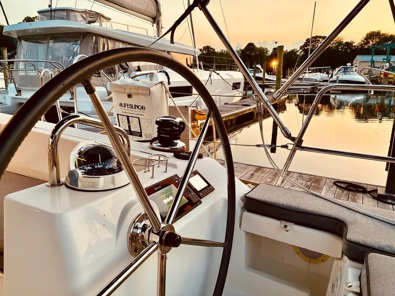 Slide: The Image of 2017 Beneteau Oceanis 45 sailboat cockpit at sunset, featuring steering wheel and navigation instruments. - 41