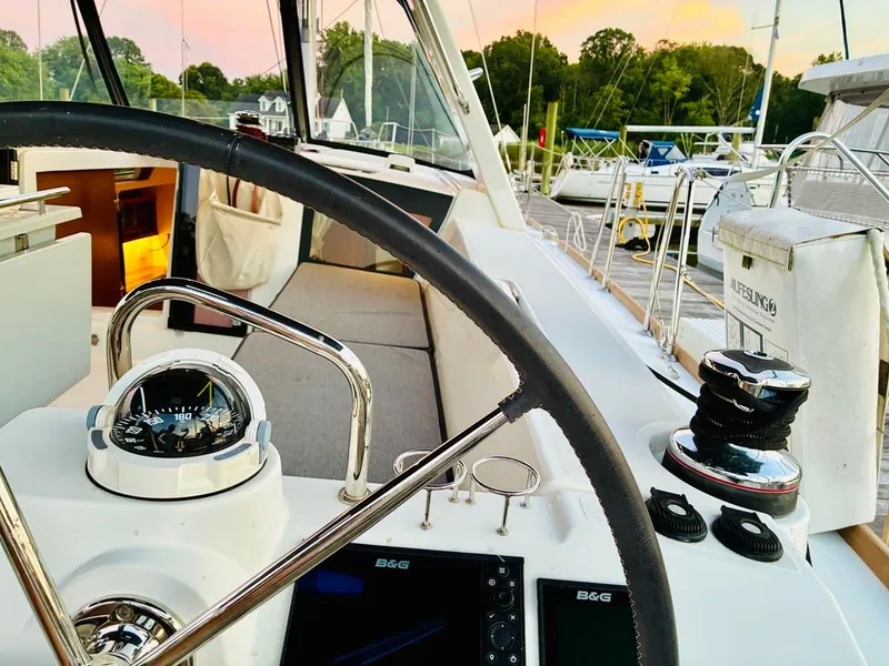Slide: The Image of Cockpit view of 2017 Beneteau Oceanis 45 sailboat at sunset, featuring steering wheel and navigation instruments. - 8