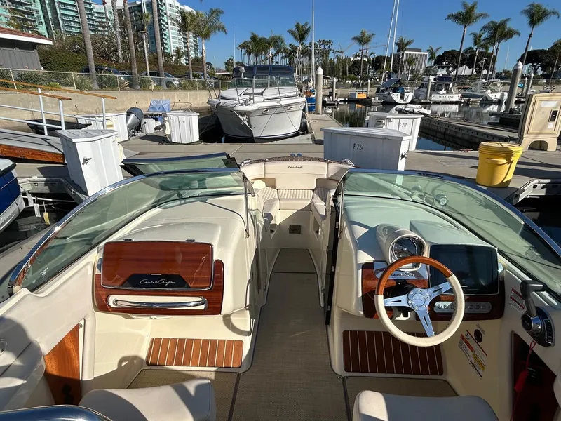 Slide: The Image of 2020 Chris-Craft 25 Launch GT boat interior at marina, featuring elegant wood accents. - 4