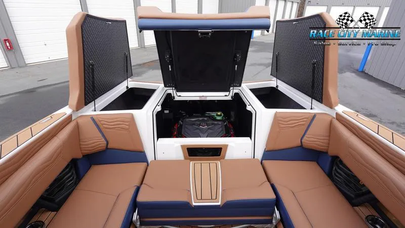 Slide: The Image of 2025 Nautique Super Air Nautique G25 interior with tan and blue seating, open storage compartments. - 18