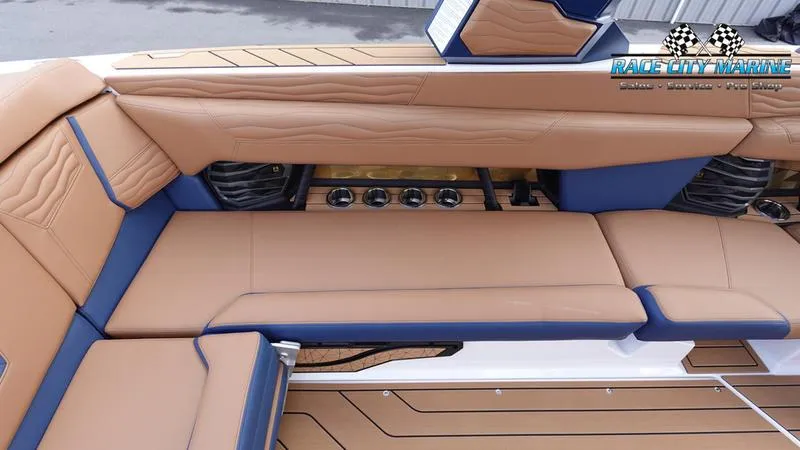 Slide: The Image of 2025 Nautique Super Air Nautique G25 interior with tan and blue seating, Race City Marine logo. - 24