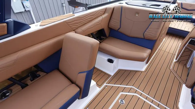 Slide: The Image of 2025 Nautique Super Air Nautique G25 interior with tan and blue seating, teak flooring. - 28