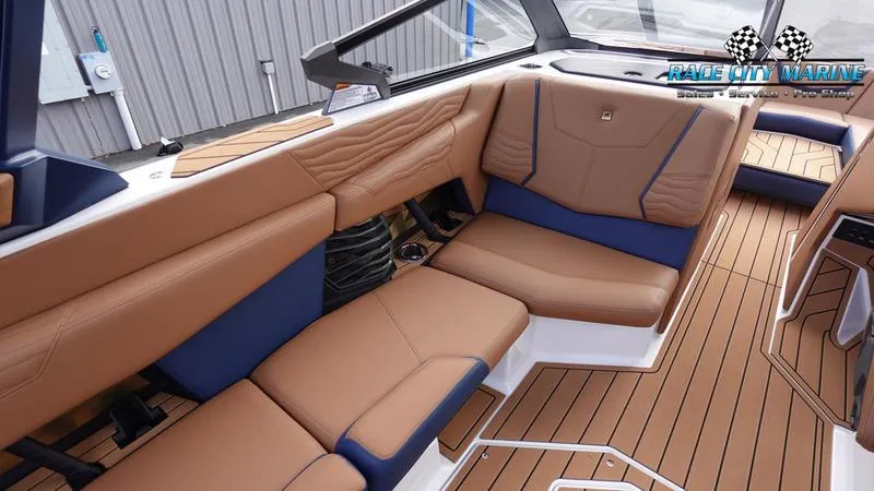Slide: The Image of 2025 Nautique Super Air Nautique G25 interior with tan and blue seating, teak flooring. - 29