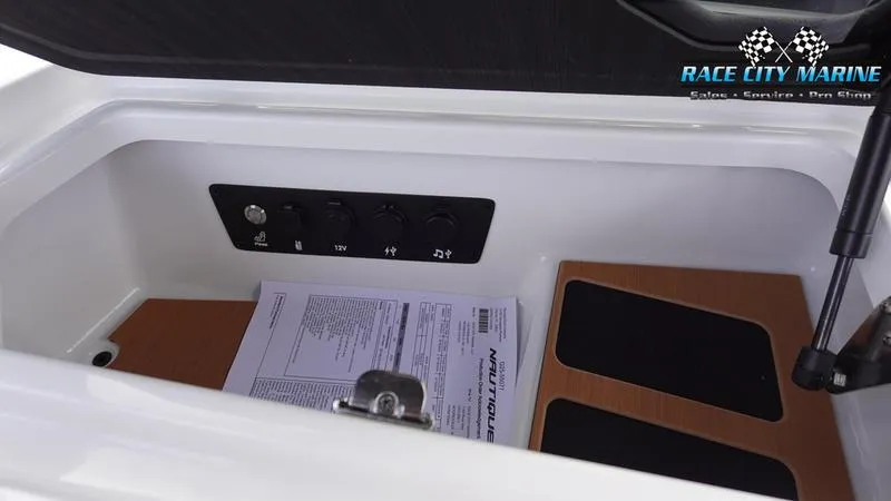 Slide: The Image of Storage compartment in 2025 Nautique Super Air Nautique G25 boat with control panel and documents. - 31