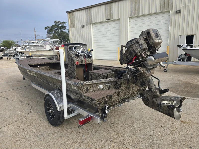 Slide: The Image of 2025 Pro-Drive 2054 X Series boat on trailer, camo design, parked outside a warehouse. - 4