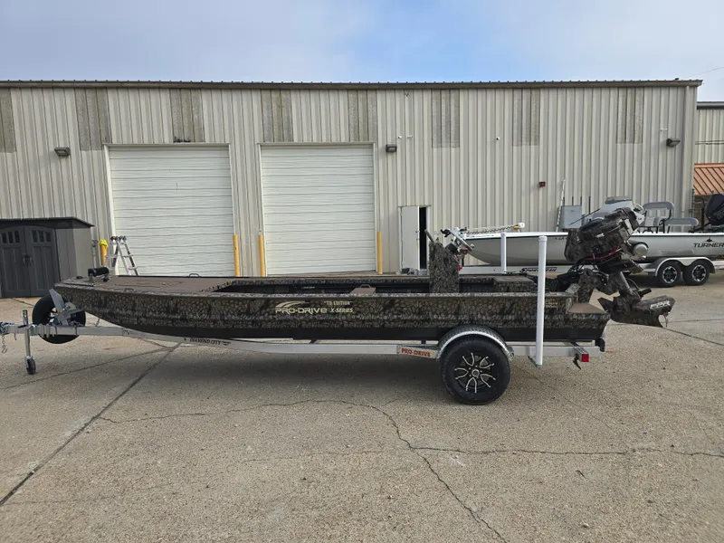 Slide: The Image of 2025 Pro-Drive 2054 X Series boat on trailer, parked outside industrial building. - 5