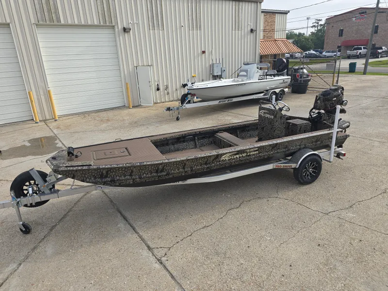 Slide: The Image of 2025 Pro-Drive 2054 X Series boat on trailer, parked outside industrial building. - 6