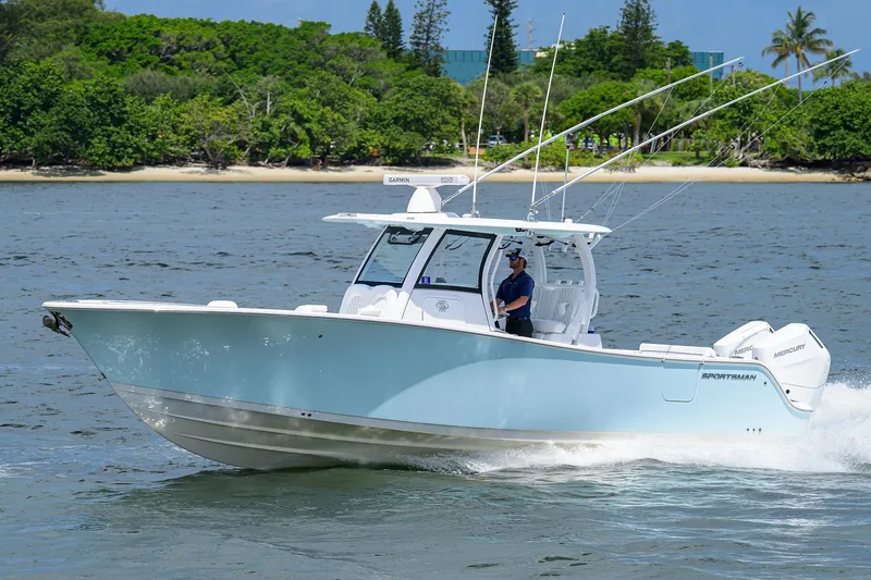 Slide: The Image of 2023 Sportsman Open 322 boat cruising on water near a lush shoreline. - 0