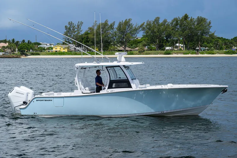 Slide: The Image of 2023 Sportsman Open 322 boat on water, side view, with trees in the background. - 1