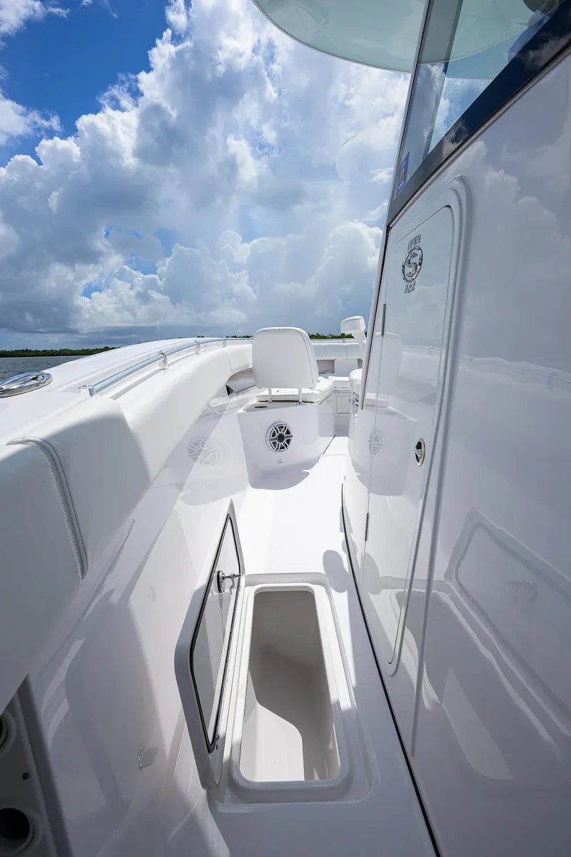 Slide: The Image of 2023 Sportsman Open 322 boat deck with storage, under a partly cloudy sky. - 13