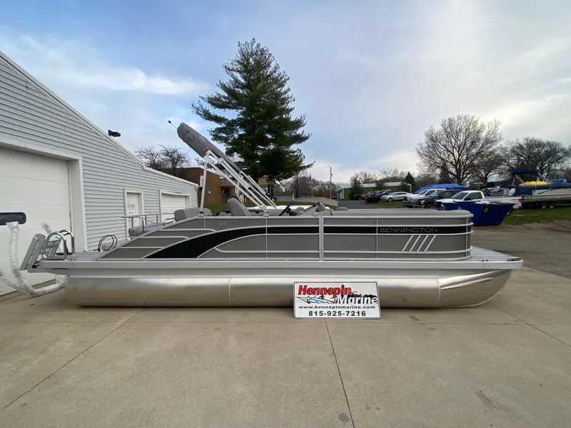 Slide: The Image of 2025 Bennington 23 LSB pontoon boat parked outdoors near a marina. - 0