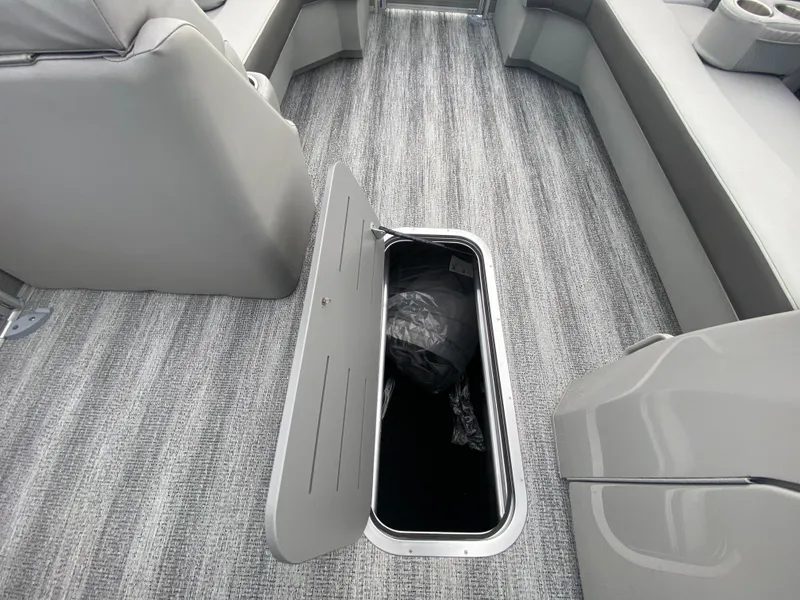 Slide: The Image of 2025 Bennington 23 LSB boat interior with open storage compartment on gray carpeted floor. - 18