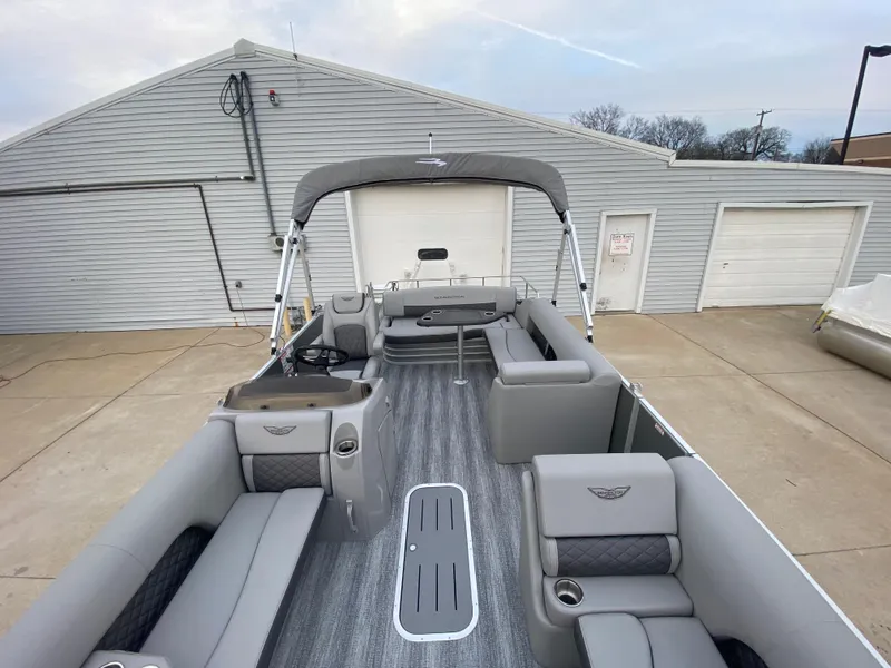 Slide: The Image of 2025 Bennington 23 LSB pontoon boat with gray interior, docked near a garage. - 34