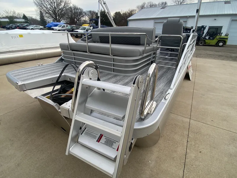 Slide: The Image of 2025 Bennington 23 LSB pontoon boat with rear ladder and seating, parked outdoors. - 7