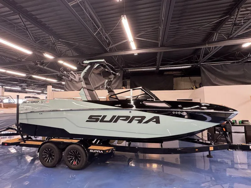 Slide: The Image of 2025 Supra SL 450 boat on trailer in showroom, sleek design, modern features. - 3