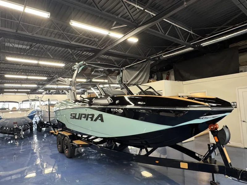Slide: The Image of 2025 Supra SL 450 boat in showroom, sleek design, black and teal color scheme. - 4