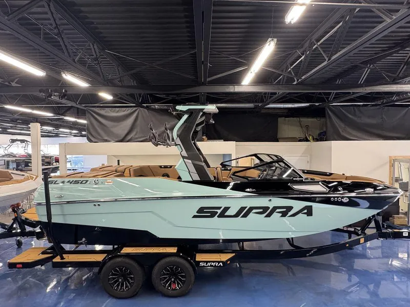 Slide: The Image of 2025 Supra SL 450 boat in showroom, sleek design, on trailer, under bright lighting. - 5
