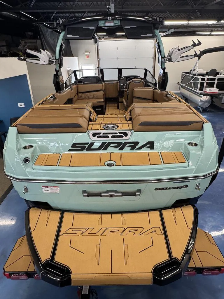 Slide: The Image of 2025 Supra SL 450 boat with tan seating and aqua exterior in showroom. - 8
