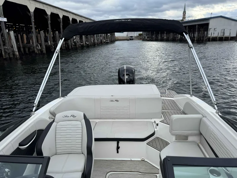 Slide: The Image of 2023 Sea Ray 190SPXO boat interior with seating and canopy on a calm waterway. - 5